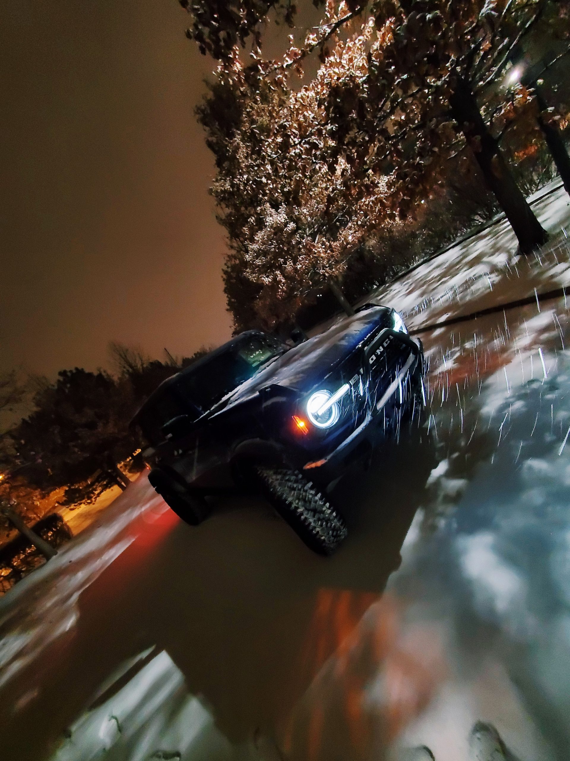 A blue Bronco shot from the front 3/4 during a snowstorm