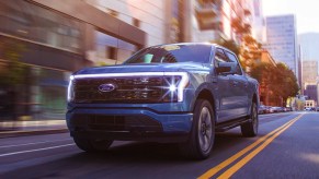 A blue 2022 Ford F-150 Lightning is driving on the road.