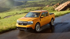 A yellow 2022 Ford Maverick is driving on a damp road.