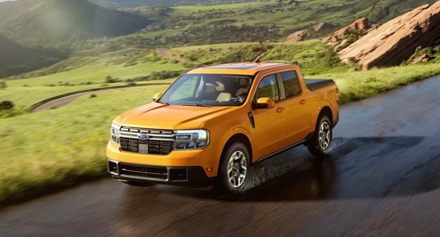 A yellow 2022 Ford Maverick is driving on a damp road.