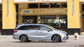 A silver 2022 Honda Odyssey minivan drives past a movie theater