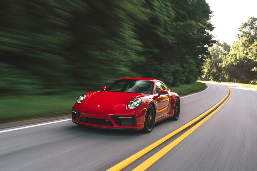 A 'Carmine Red' 2022 Porsche 911 Carrera GTS drives down a forest road