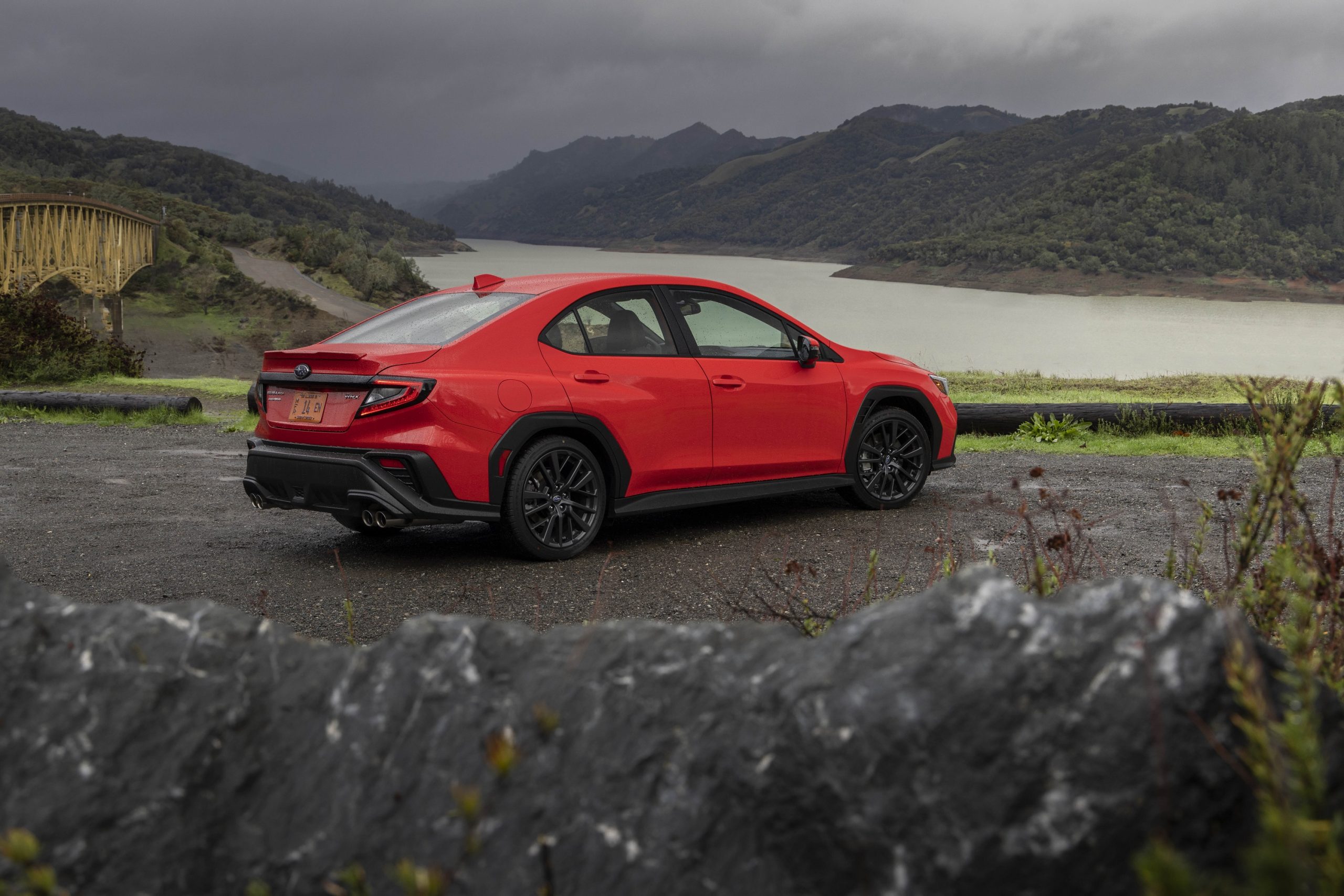 A red 2022 Subaru WRX shot from the rear 3/4 on a rainy day