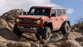 Cyber Orange 2022 Ford Bronco Raptor driving over rocky terrain