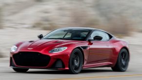 A red Aston Martin DBS driving fast on a road