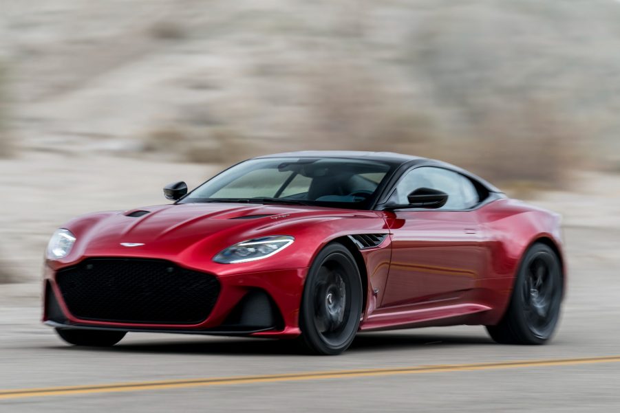 A red Aston Martin DBS driving fast on a road