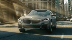 Fully loaded new gray 2022 BMW 7 Series M760i xDrive Sedan driving across a bridge