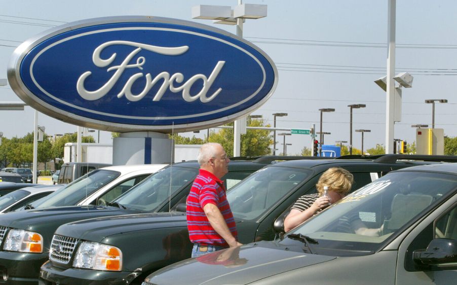 Front of Ford dealership with new cars and Ford sign.