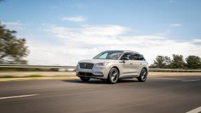 A white 2021 Lincoln Corsair Grand Touring driving down a road.