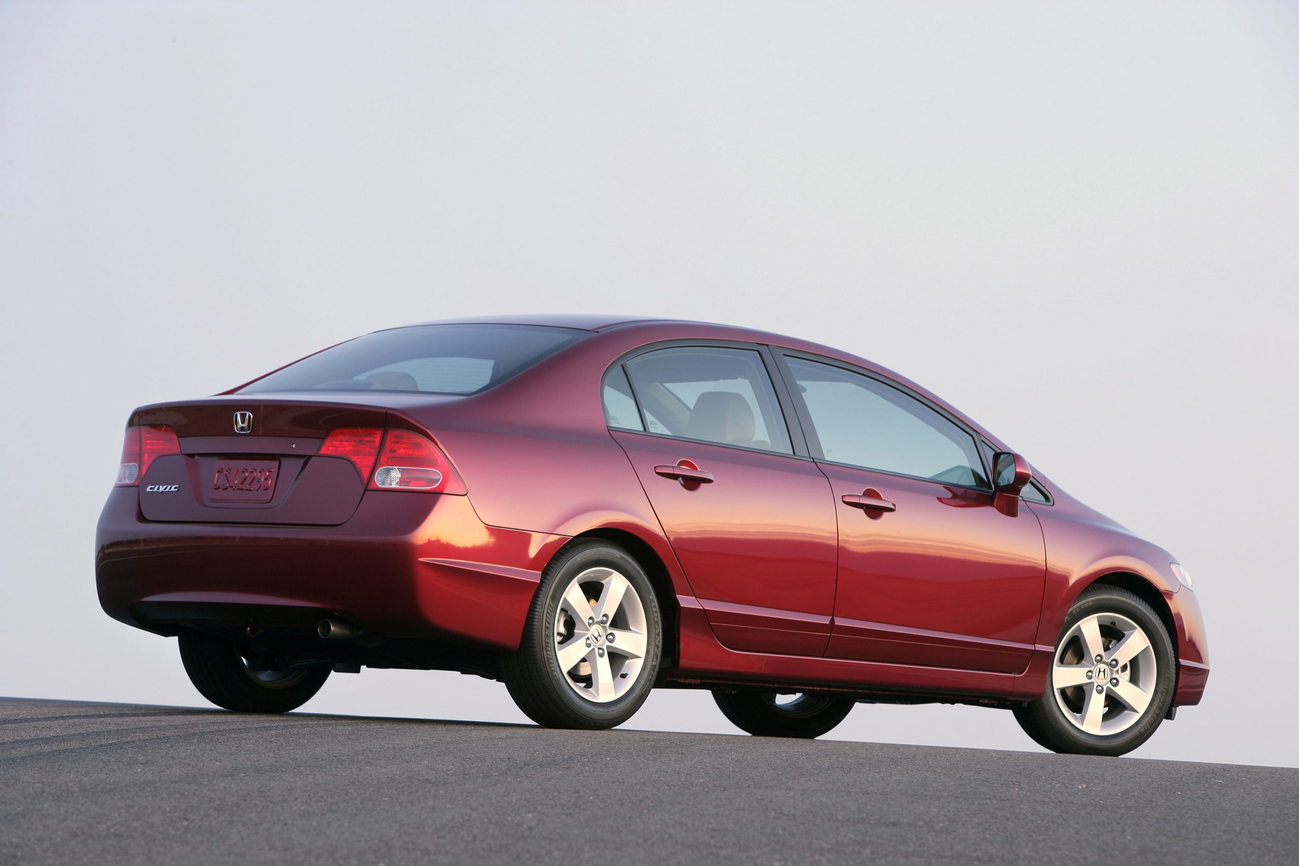 A red 8th gen sedan shot from the rear 3/4