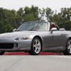 A grey AP1 generation Honda S2000 roadster shot from the front 3/4 at a race track