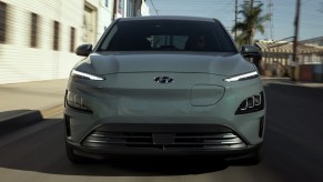 A gray Hyundai Kona Electric is driving on the road.