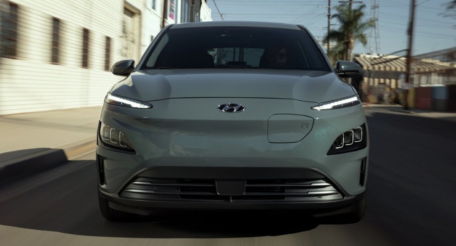 A gray Hyundai Kona Electric is driving on the road.