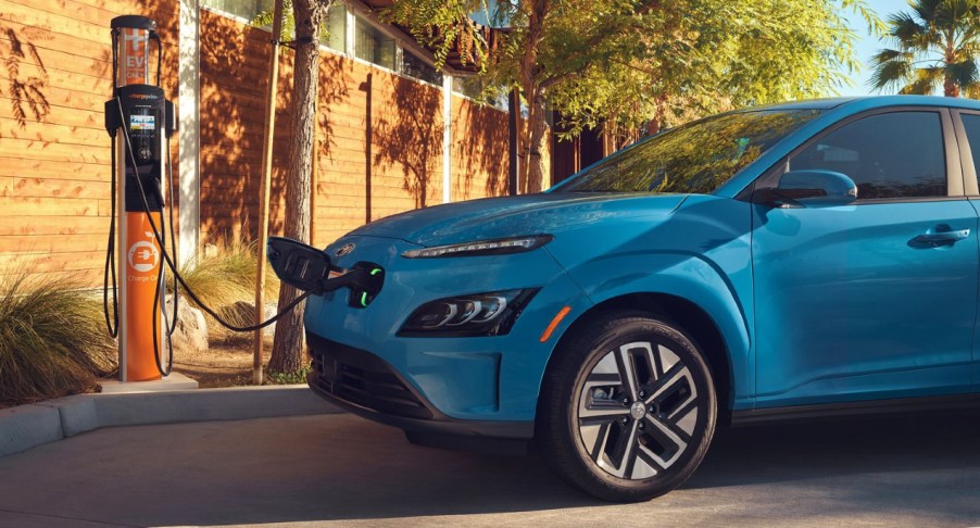 A blue 2022 Hyundai Kona Electric SUV is charging.