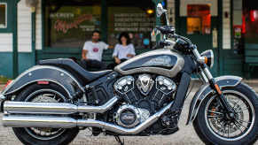 The Indian Scout motorcycle parked on a gravel lot outside of a store