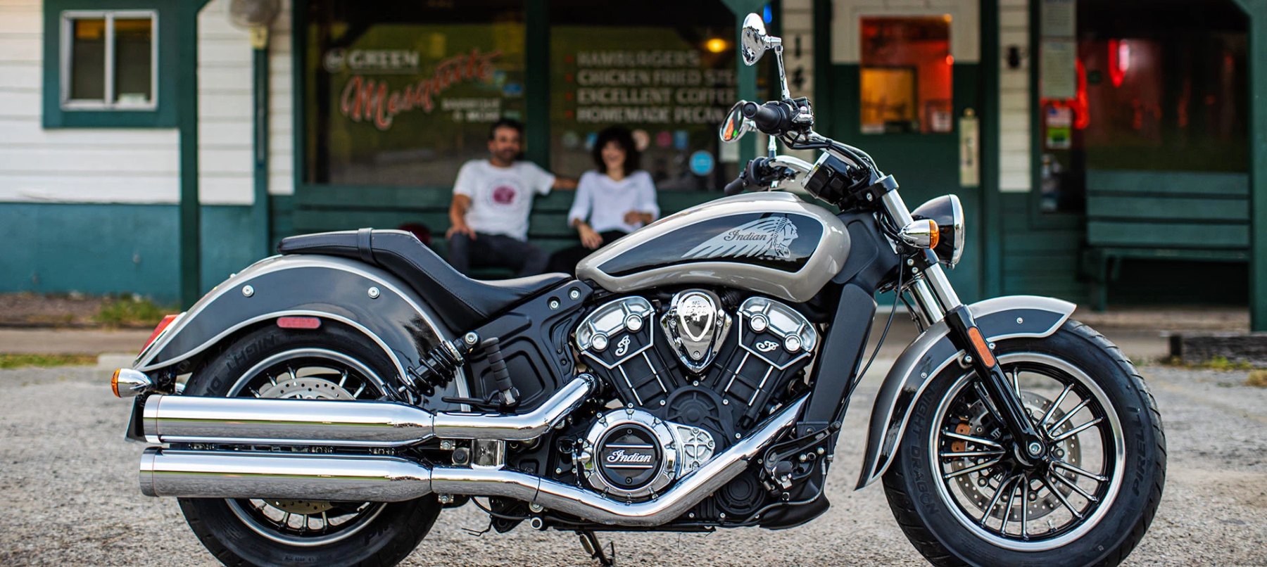 The Indian Scout motorcycle parked on a gravel lot outside of a store