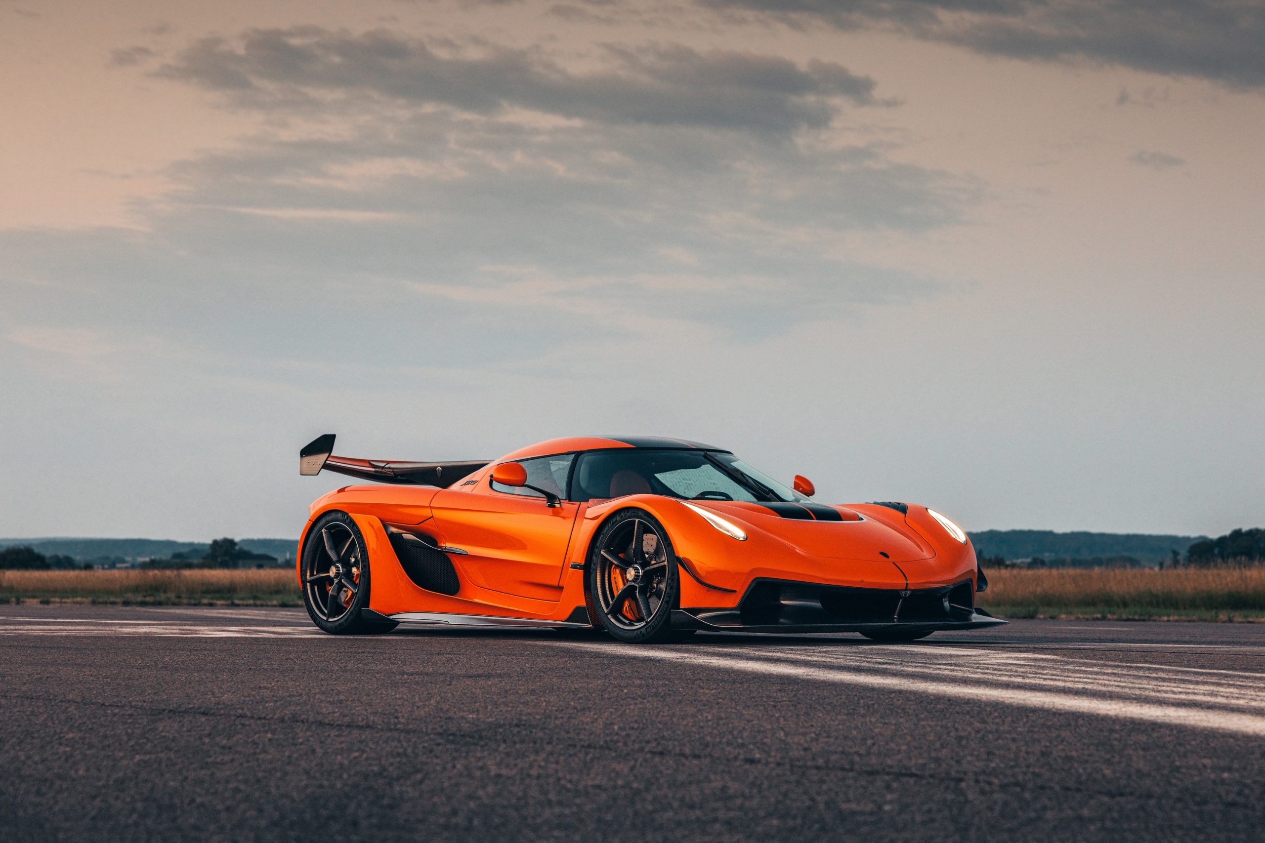 An orange Koenigsegg Jesko shot on a runway at sunset