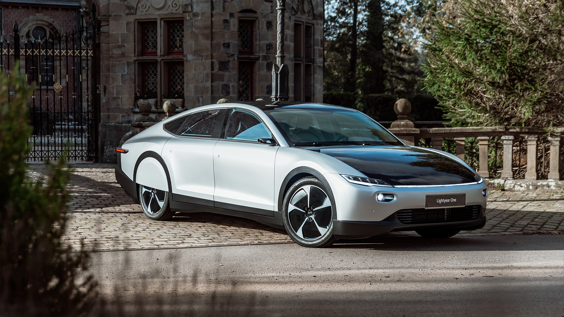 The Lightyear One solar-electric 5-door liftback model parked outside a stone manor