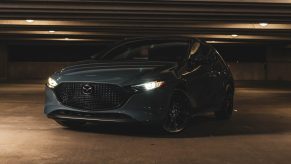 A grey Mazda 3 shot from the front 3/4 in a parking garage