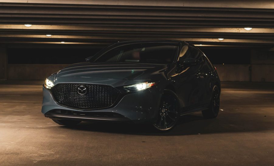 A grey Mazda 3 shot from the front 3/4 in a parking garage