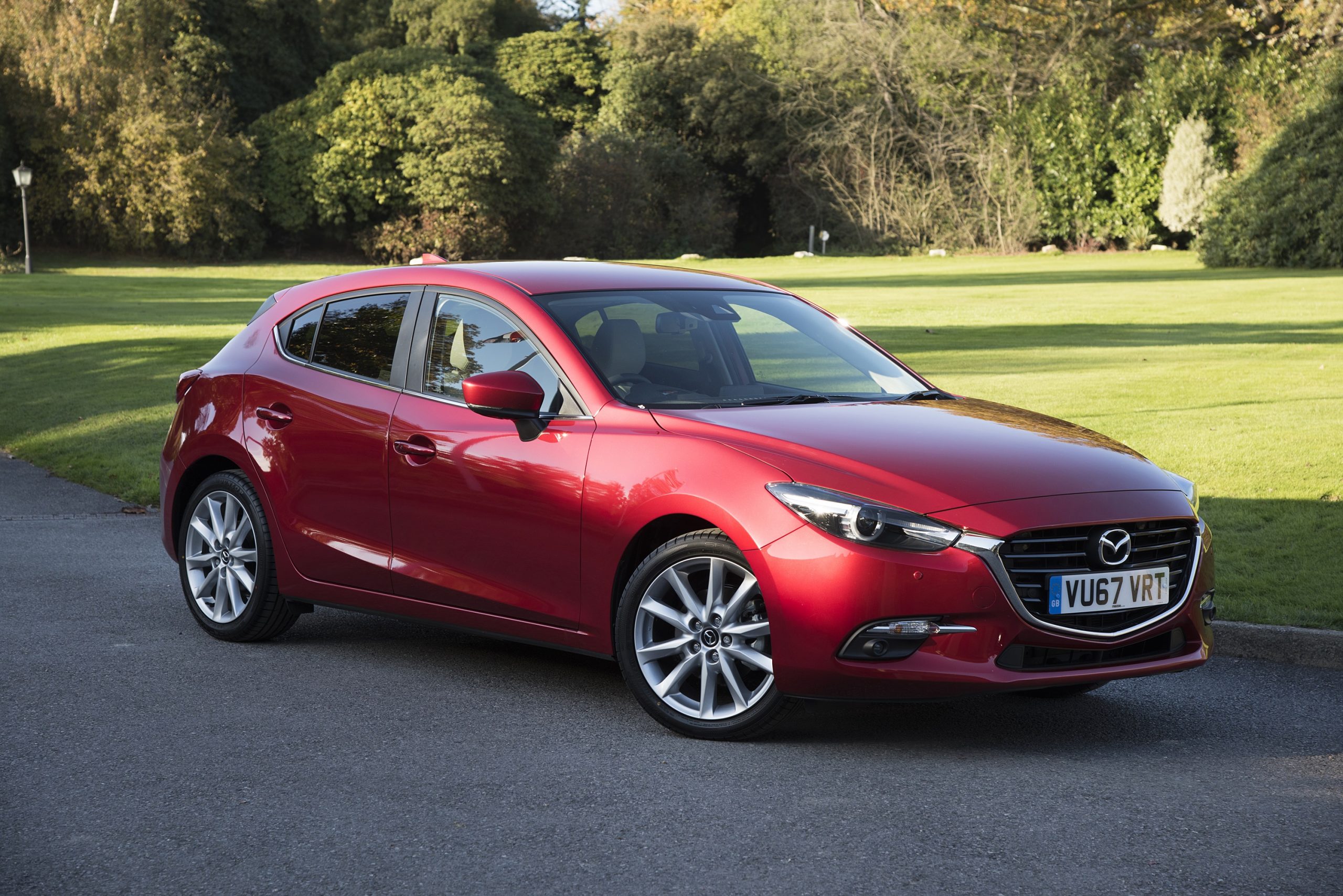 A red Mazda3 hatchback shot from the front 3/4 