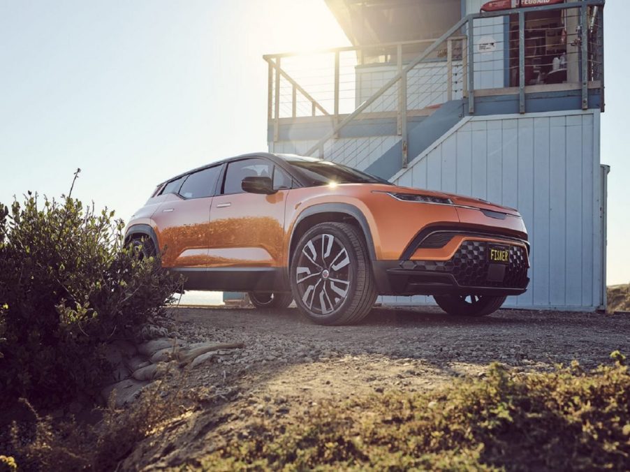 Orange 2023 Fisker Ocean, one of the cheapest electric crossover SUVs available to buy in 2022, parked next to a lifeguard tower