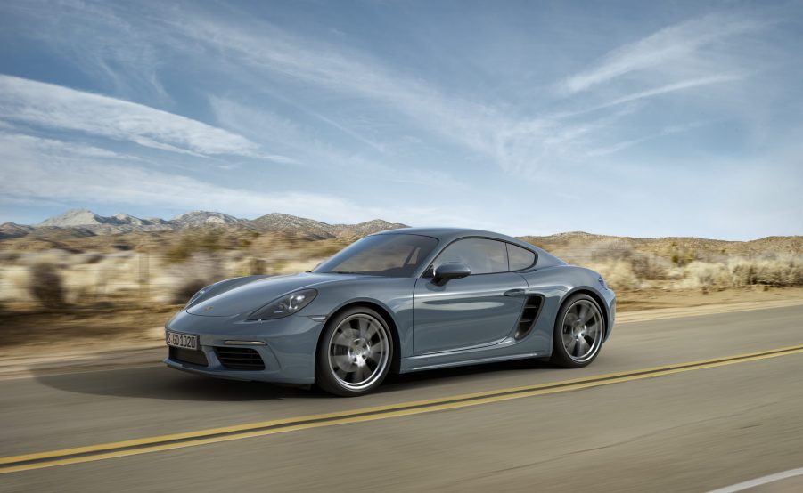 A blue/gray Porsche 718 Cayman driving on a desert road