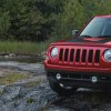 A red Jeep Patriot parked next to a tent.