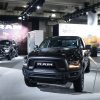 Black Ram truck with others behind it, possibly a Ram 1500, in an indoor environment.