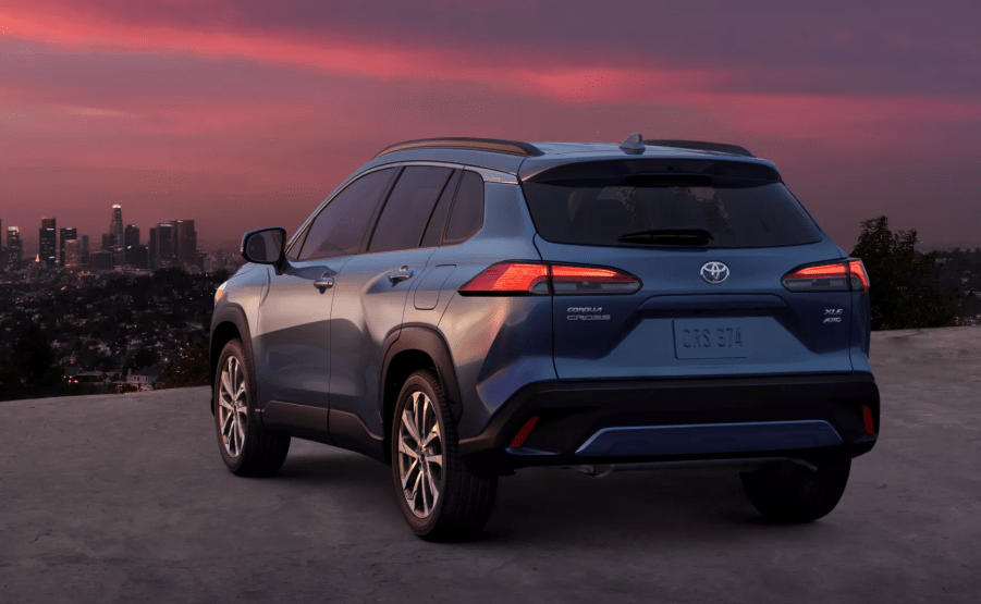 Rear view of Blue Crush Metallic 2022 Toyota Corolla Cross with a city skyline in the background