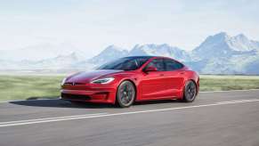 Red Tesla Model S driving, highlighting how EV car batteries destroy the environment and violate human rights