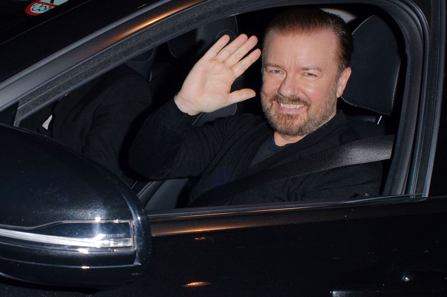 Ricky Gervais waving from a black car.