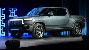 A light blue Rivian R1T displayed on a platform in an indoor environment.