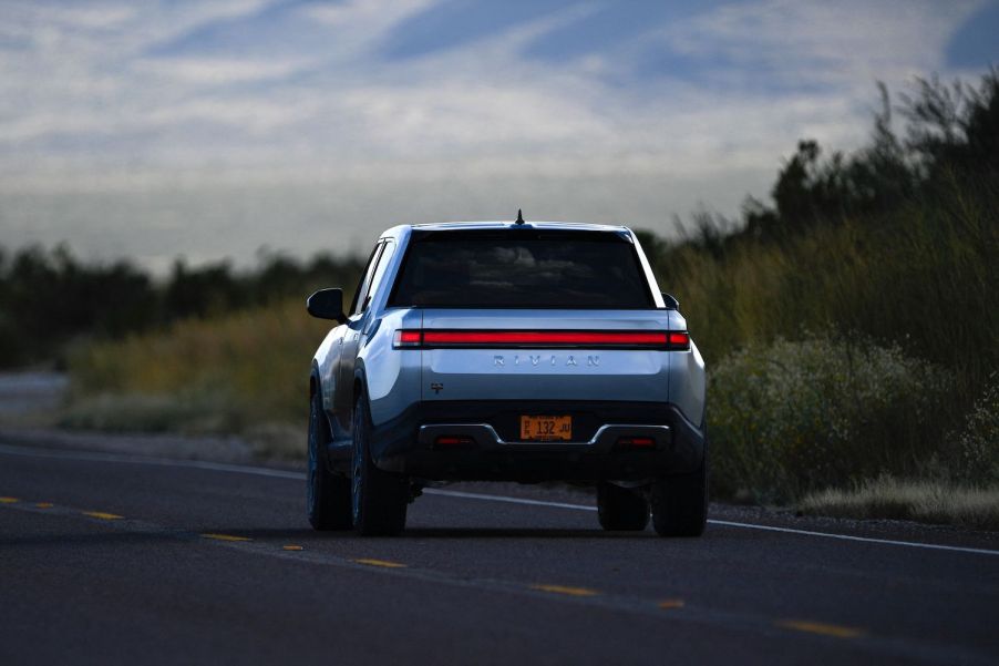 A silver Rivian R1T electric pickup driving on the highway.