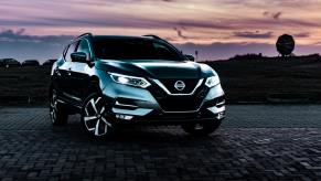 A dark colored 2022 Nissan Rogue Sport with a sunset i the background.