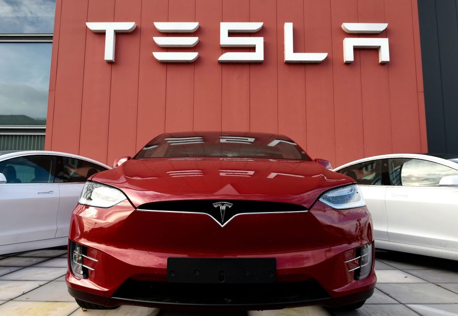 A red Tesla Model 3 in front of one of the brand's showrooms