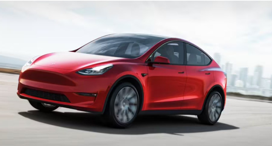 A red Tesla Model Y is driving on the road.