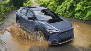 A blue 2023 Subaru Solterra is driving in the mud.