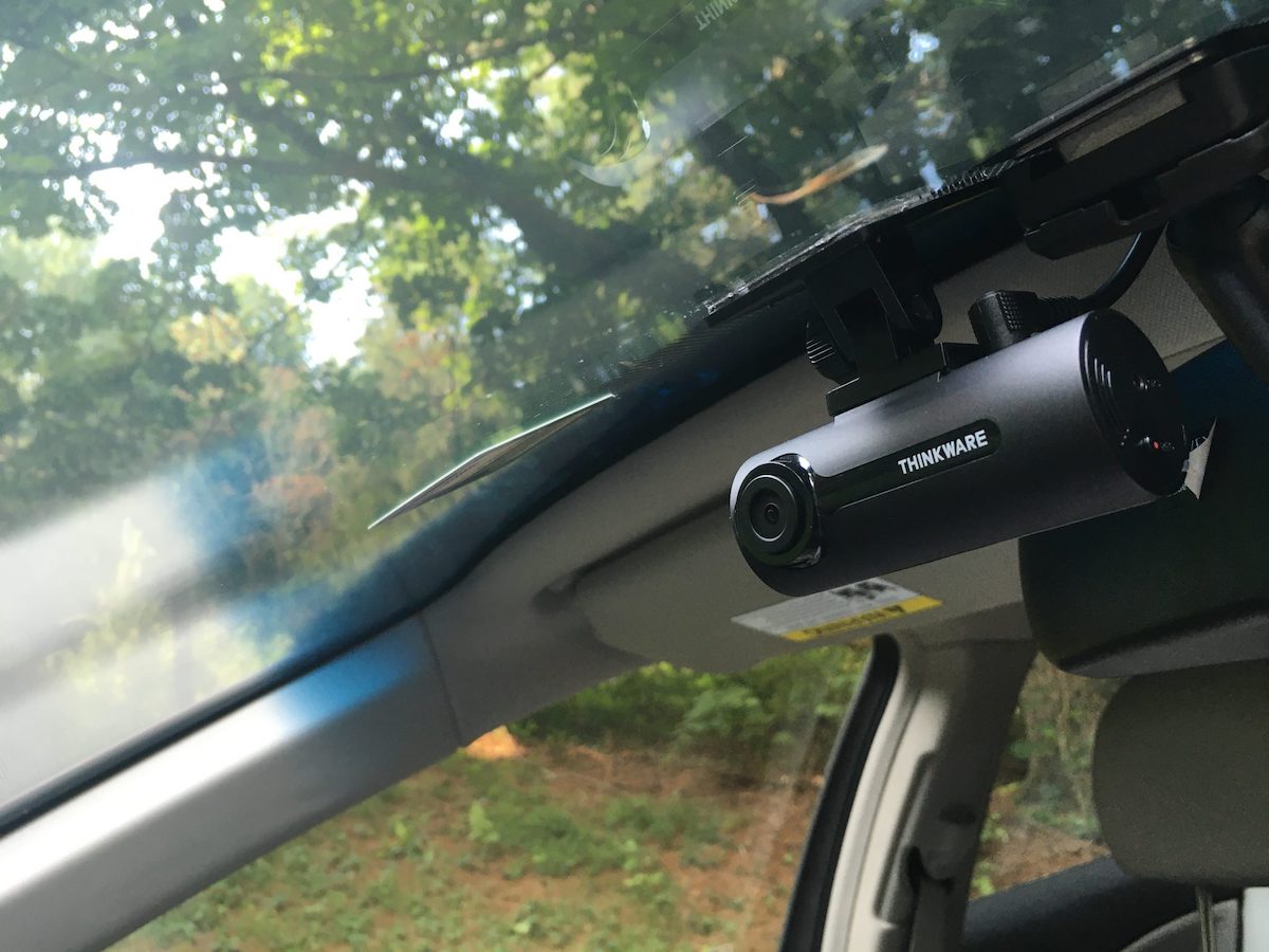 A Thinkware F70 dashcam mounted behind a rearview mirror in a car