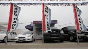 A used car dealership with flags and various cars out front.