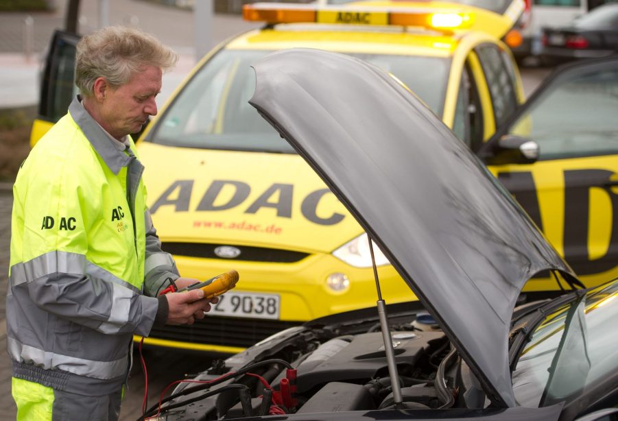 A service man jump starts a car battery