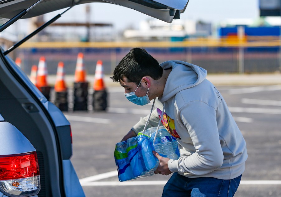 A man places water bottles into the back of a car in winter 2021 in Galveston, Texas