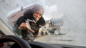 A woman scraping a frozen car windshield window in Baden-Wuerttemberg, Ballmertshofen, Dischingen, Germany