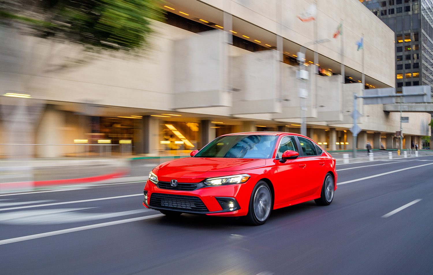 Red 2022 Honda Civic sedan touring driving on city street