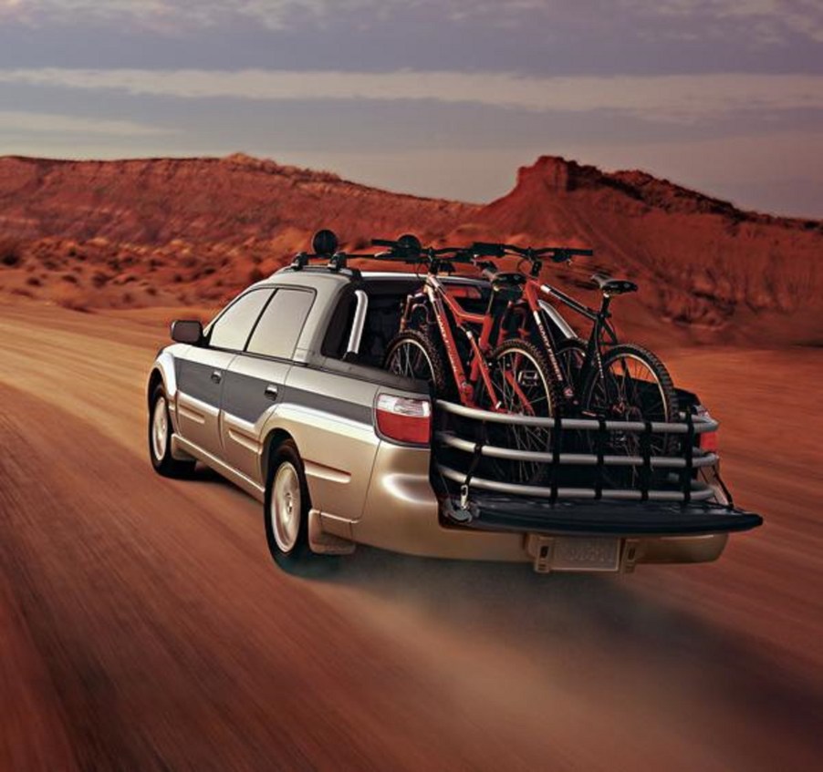 The rear 3/4 view of a green-and-tan 2005 Subaru Baja driving through the desert