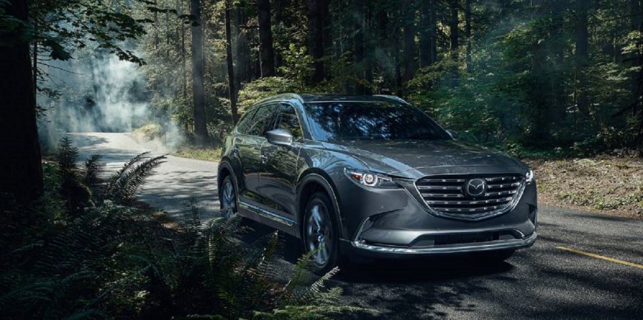 A dark blue 2022 Mazda CX-9 splashing through a puddle.