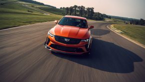 A front view of an orange 2022 Cadillac CT4-V Blackwing exiting a corner at a race track.