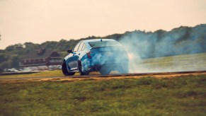 Electric Blue Cadillac CT5-V Blackwing drifting around a corner on a race track shot from behind