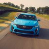 A front view of a blue 2022 Cadillac CT5-V Blackwing cornering on a race track with trees in the background.