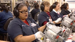 A row of Mexican women assembling car stereos for the GMC Sierra.